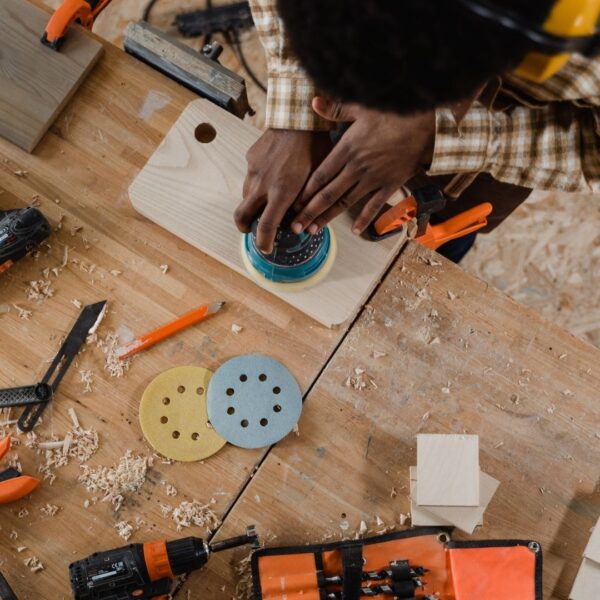 overhead view of person holding orbital sander to smooth wood