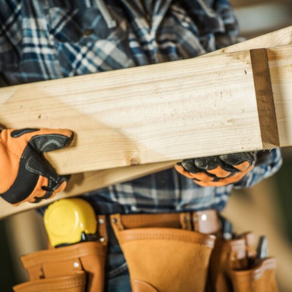 A person wearing safety gloves while handling lumber.